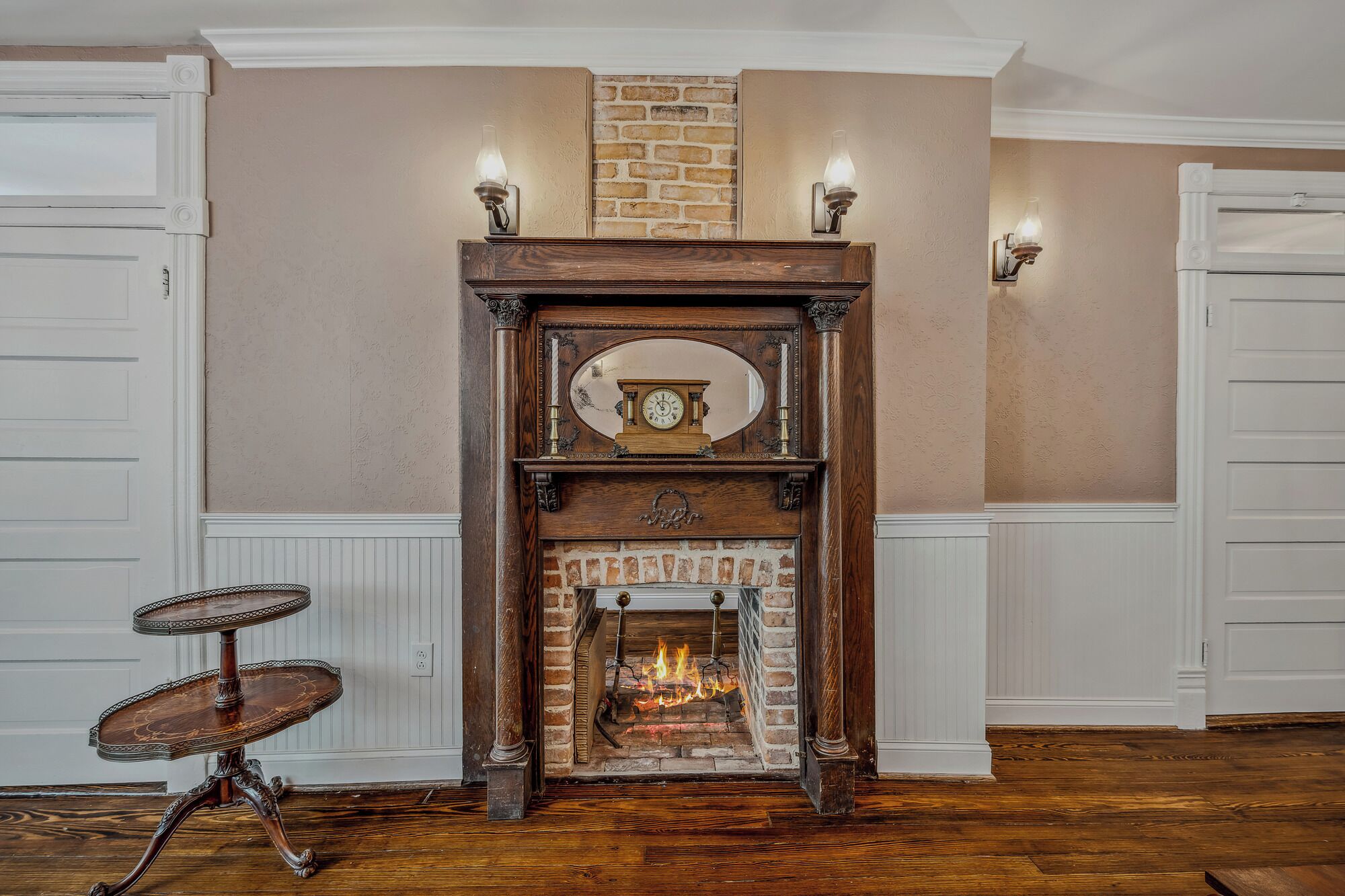 A fireplace with a clock above it, flanked by two wall sconces.