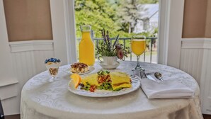 Een gedekte tafel met een maaltijd, waaronder een omelet, een glas sinaasappelsap en een kom yoghurt met bosbessen.