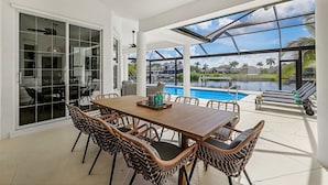 A spacious patio with a dining table and chairs, a pool, and a view of the surrounding area. - Luxe Home, Pool, Boat Rental, Hot tub, & Fire pit (Cape Coral)