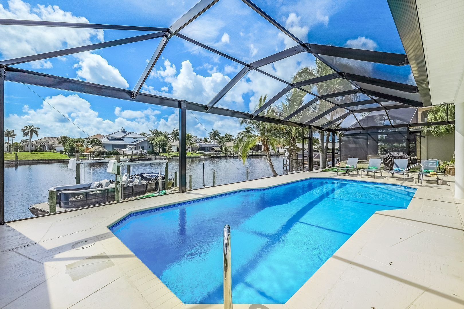 A covered swimming pool with a view of a lake and houses in the background.