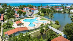 Um resort com uma piscina grande, uma ponte e vista para o oceano.