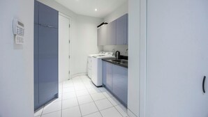 A compact kitchen with a washing machine, a sink, and cabinets. - Big Beautiful house in Richmond centre (Richmond)