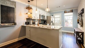 Una cocina moderna con una isla grande, armarios blancos y suelo de madera oscura.