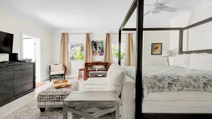 Quarto com cama de dossel, sofá, mesa de jantar e televisão.
