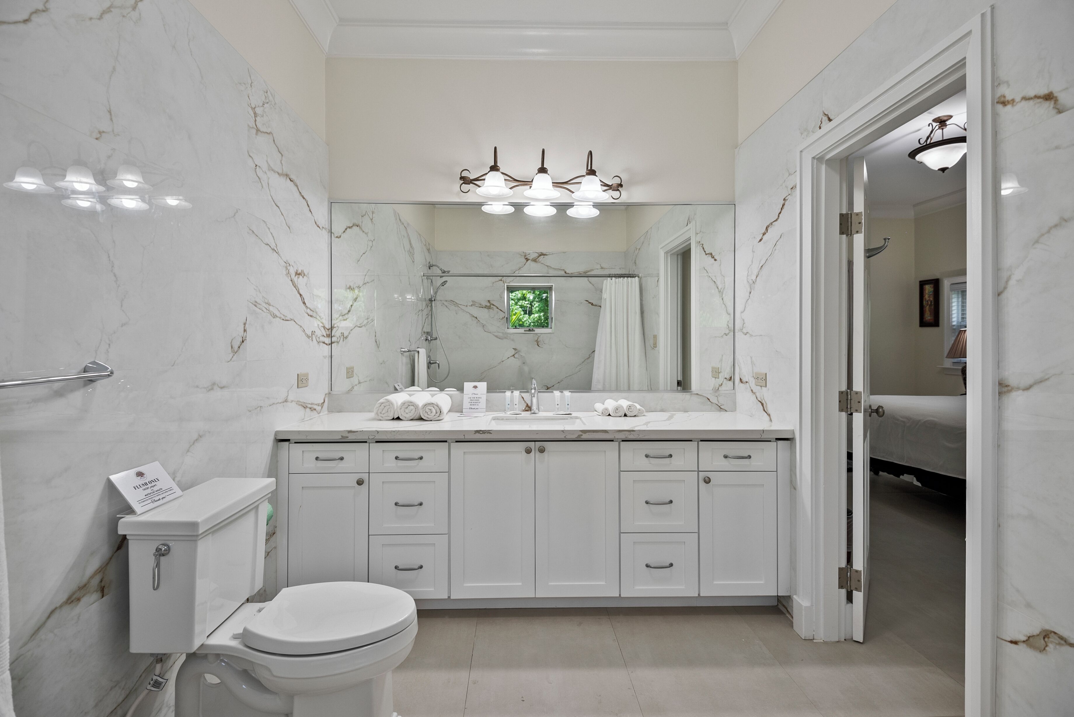 A modern bathroom with a marble backsplash, a large mirror, and a walk-in shower.