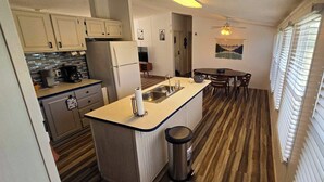 Una cocina compacta con una isla central, un comedor y vistas al exterior.