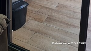 A modern kitchen with a built-in sink and cabinets, a black countertop, and a view of a balcony with a building in the background. - Luxuoso AP no Martim Praia Clube - Martim de Sá (Martim de Sá Caraguatatuba)