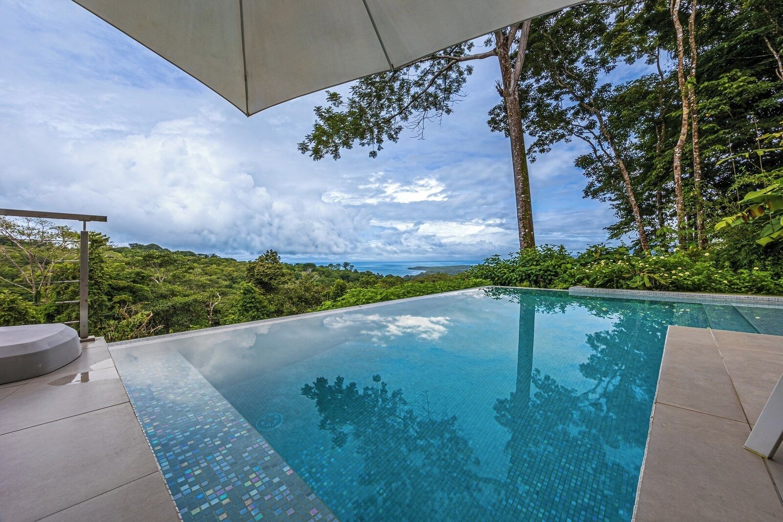 An infinity pool with a clear view of the ocean and lush greenery.