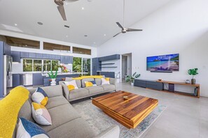 A modern living room with a sectional sofa, a wooden coffee table, and a TV mounted on the wall.