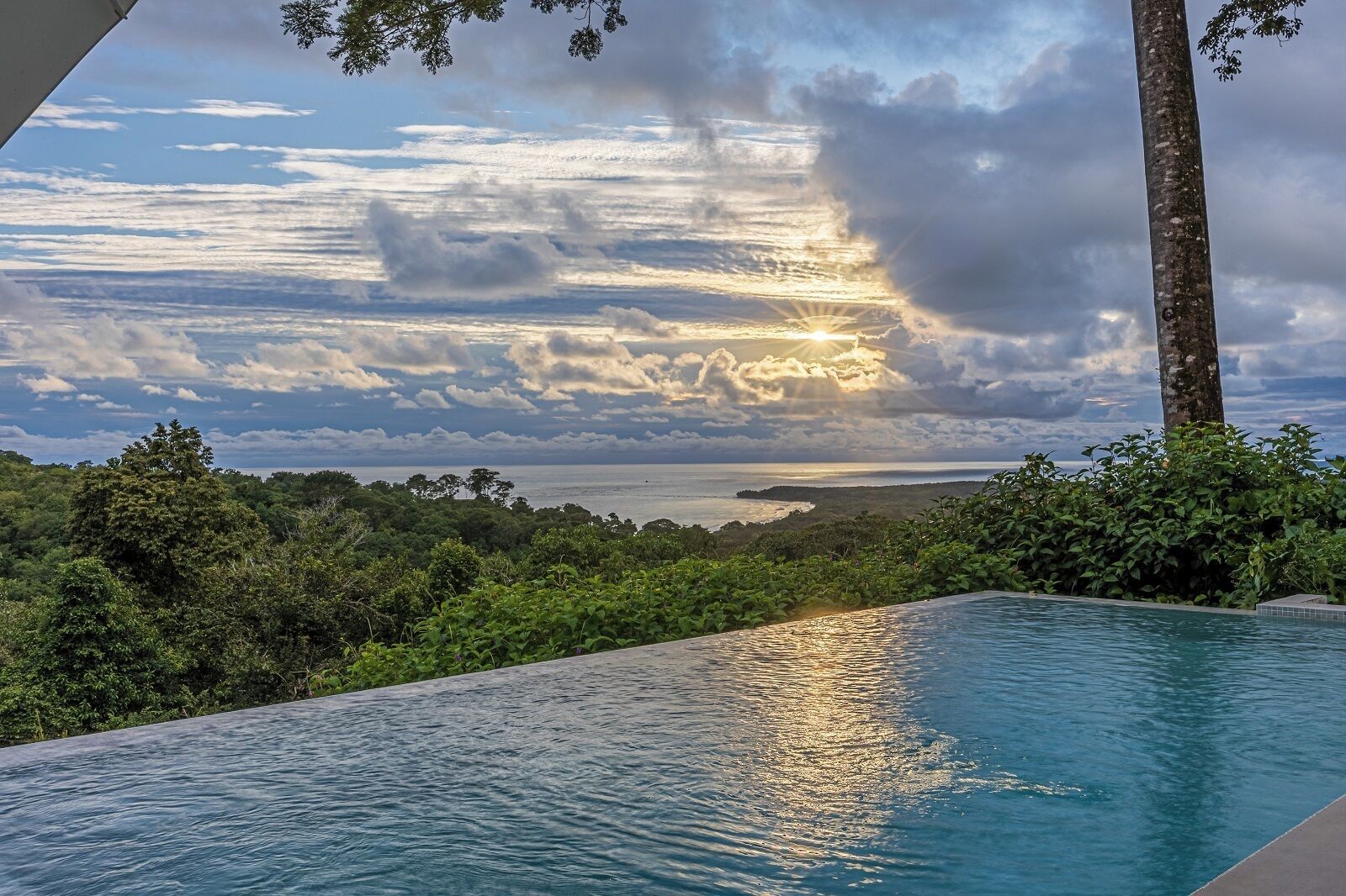 An infinity pool with a view of the ocean and a sunset.