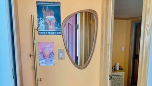 A room with a purple furry bench, a heart-shaped mirror, and a poster on the wall. - Catskill Cabin Apres Ski (Shandaken)