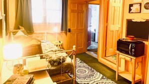 A cozy room with a bed, bedside table, lamp, and a television on a stand. - Catskill Cabin Apres Ski (Shandaken)