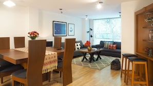 Una sala moderna con comedor, un conjunto de sofás, una mesa de centro y una estantería.