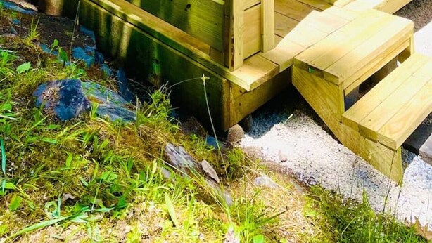 Une terrasse en bois avec un hamac et une table entourée de chaises.