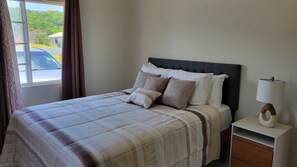 Relax in a serene bedroom with a large bed and a window offering a view of the surrounding area.