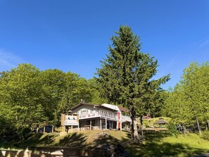 A building with a covered outdoor area, surrounded by trees. - Red Peacock Catskill Cabin sleeps four 6 (Shandaken)