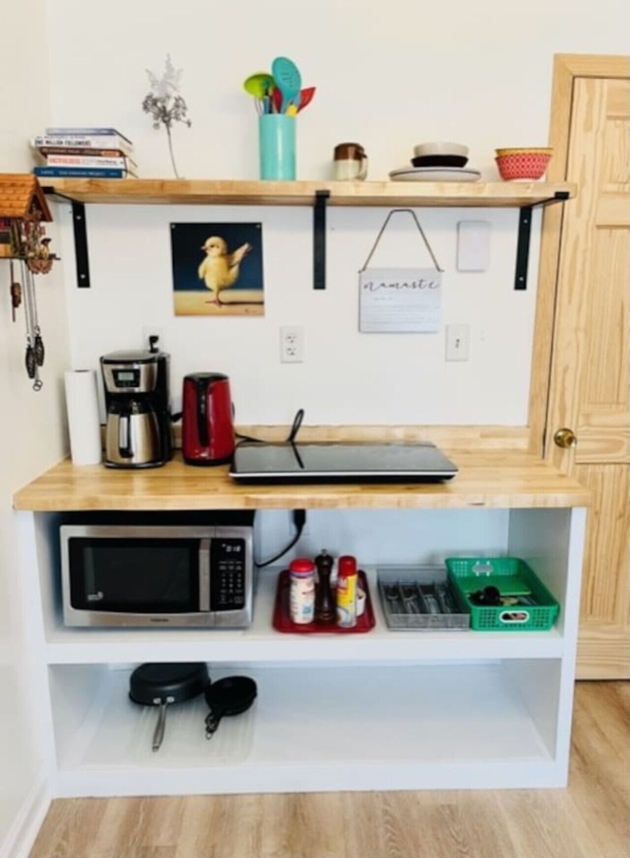 Eine kompakte Küche mit Mikrowelle, Kaffeemaschine und einer kleinen Arbeitsfläche.