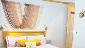 Une chambre à coucher avec un lit, une tête de lit en bois, une horloge murale et une porte portant une plaque avec un numéro.