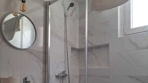 A bathroom with a glass-enclosed shower, a sink with a mirror, and a toilet.