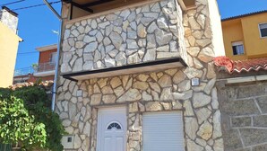 A two-story stone building with a white door and a small window.