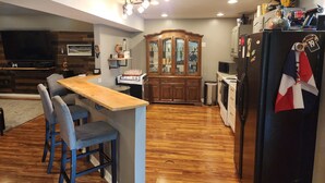 Una cocina moderna con una barra de madera, taburetes, un mueble grande de madera y un refrigerador con imanes.