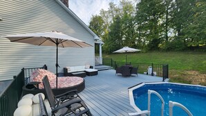 Una terraza con mobiliario exterior, piscina y una zona cubierta.