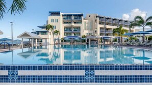 A hotel with a swimming pool, multiple balconies, and palm trees. - Flamingo Beach by Hilton: Oceanfront Resort, Pools & Spacious Studios To Relax! (Philipsburg)