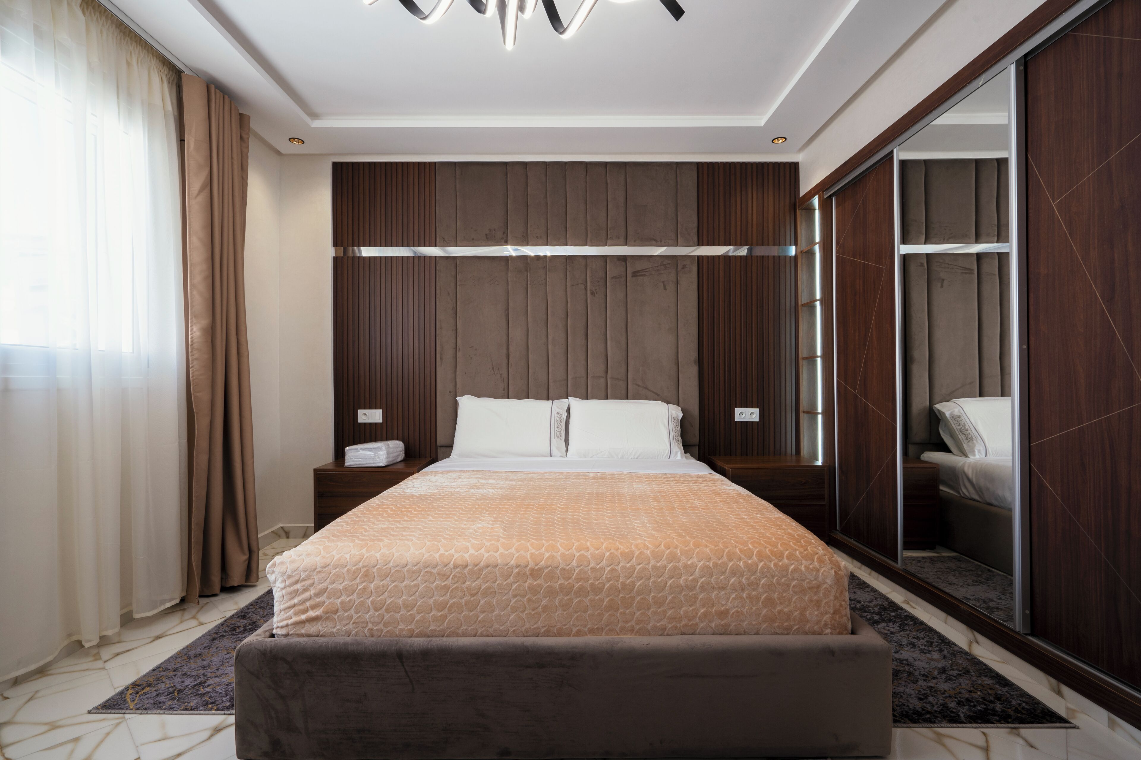 A modern hotel room with a large bed, a wardrobe, and a mirror.