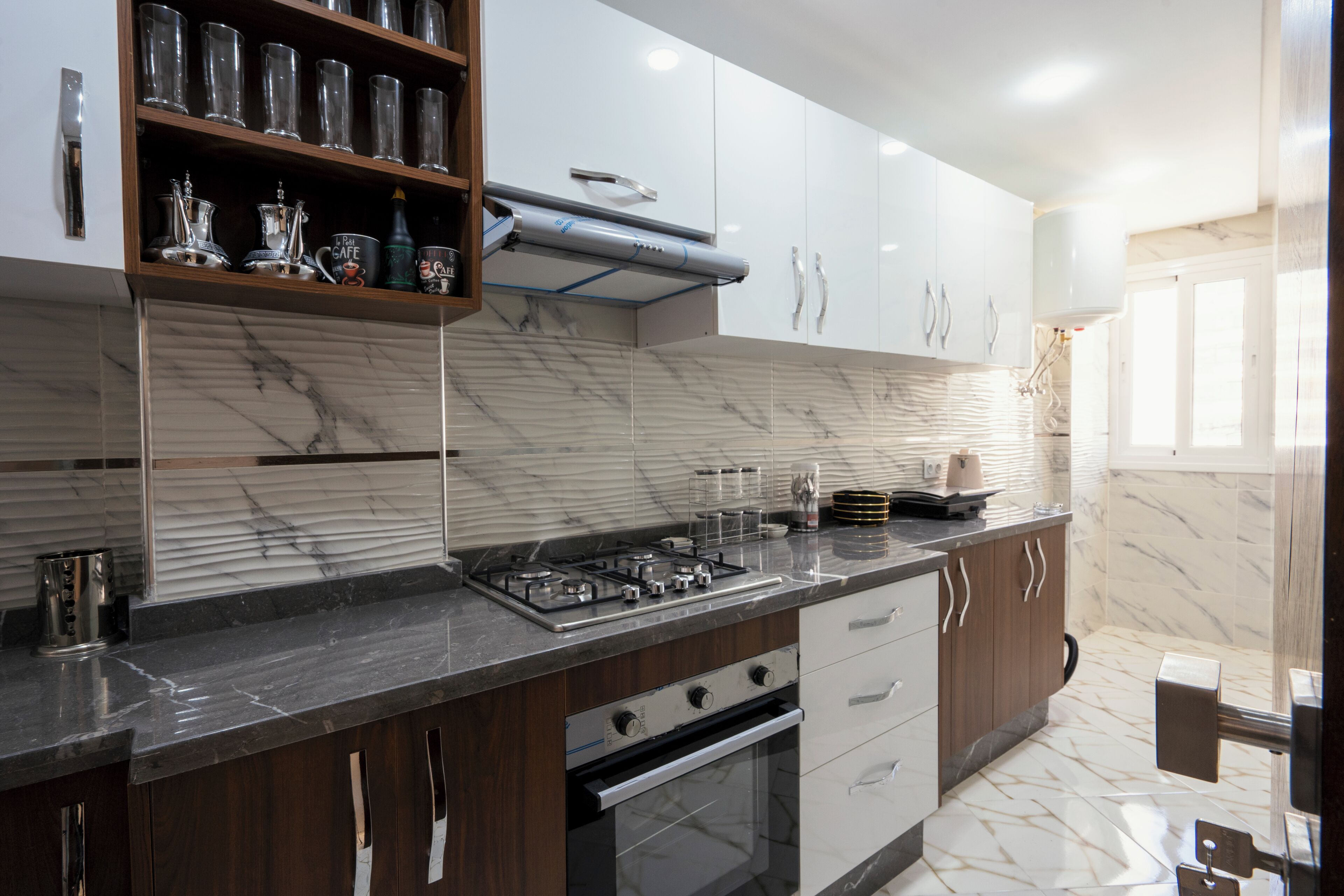 Een moderne keuken met een marmeren spatwand, roestvrijstalen apparatuur en houten keukenkastjes.