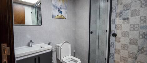 Un baño moderno con cabina de ducha de vidrio, inodoro blanco y tocador con espejo.