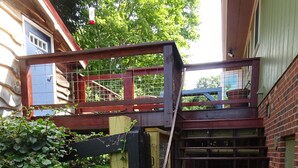 Eine Holztreppe führt zu einem überdachten Bereich mit einem Metallgitter.