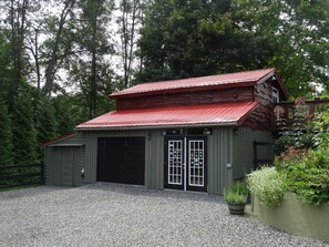 A rustic wooden building with a red roof, a garage, and a gravel driveway. - Vogelsang guesthouse, 5 minute walk to downtown West Jefferson. (West Jefferson)