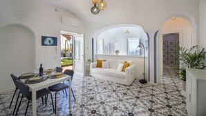Un coin repas avec une table dressée pour quatre personnes, un canapé blanc et un sol à motifs.