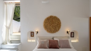 A bedroom with a bed, a staircase, a round wall decoration, and two wall-mounted lights. - Punta di Diamante - 200 Steps to Heaven (Praiano)
