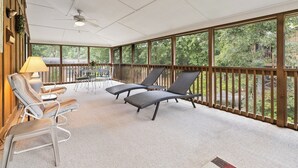A covered outdoor area with lounge chairs, a table, and a ceiling fan. - Welcome to A Glimpse of the Lake – Your Ideal Lakeside Retreat (Bronston)