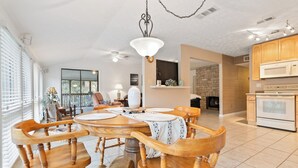 A spacious dining area with a large wooden table and chairs, a chandelier, and a kitchen in the background. - Welcome to A Glimpse of the Lake – Your Ideal Lakeside Retreat (Bronston)