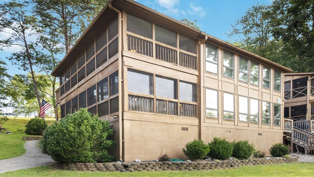 A two-story building with large windows and a balcony, surrounded by greenery and a flag. - Welcome to A Glimpse of the Lake – Your Ideal Lakeside Retreat (Bronston)