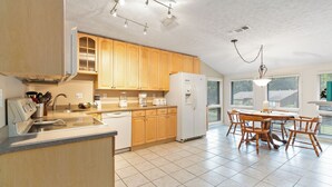 A kitchen with wooden cabinets, a refrigerator, a stove, and a dining table with chairs. - Welcome to A Glimpse of the Lake – Your Ideal Lakeside Retreat (Bronston)