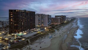 Un hôtel situé en bord de mer, composé de plusieurs immeubles de grande hauteur, avec une plage et un parking.
