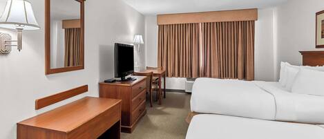 Une chambre d’hôtel équipée d’un lit, d’un bureau, d’une chaise, d’une télévision et d’une grande fenêtre avec des rideaux.