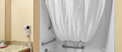 A bathroom with a white bathtub, a hairdryer, and a towel rack.