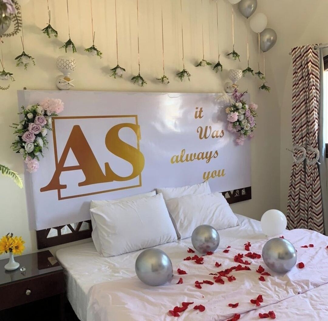 Habitación de hotel con un gran cabecero decorativo, una cama con ropa blanca y una pared con un cartel que dice 'it Was always you'.