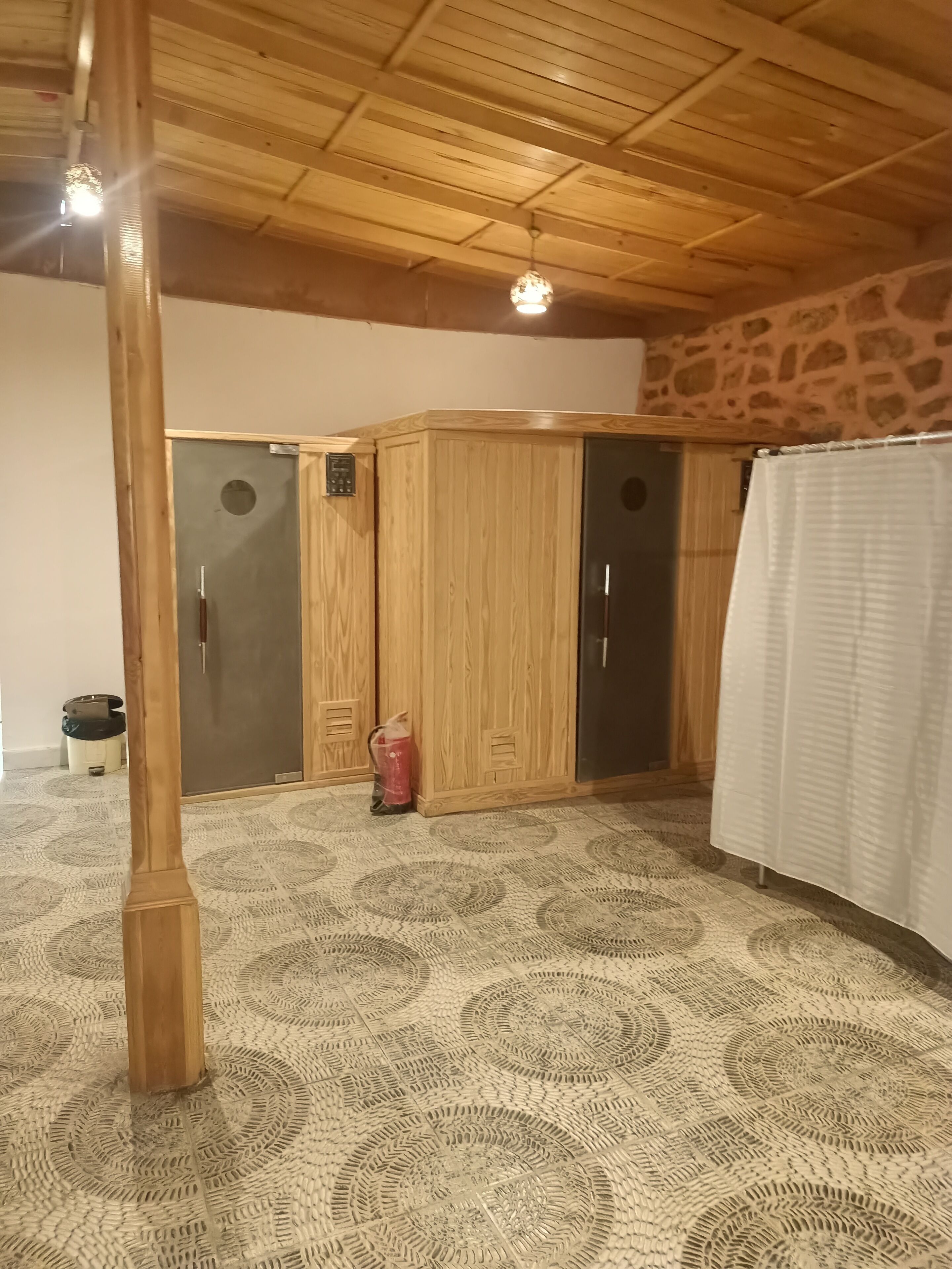 A room with a patterned floor, wooden wardrobe, and a stone wall.