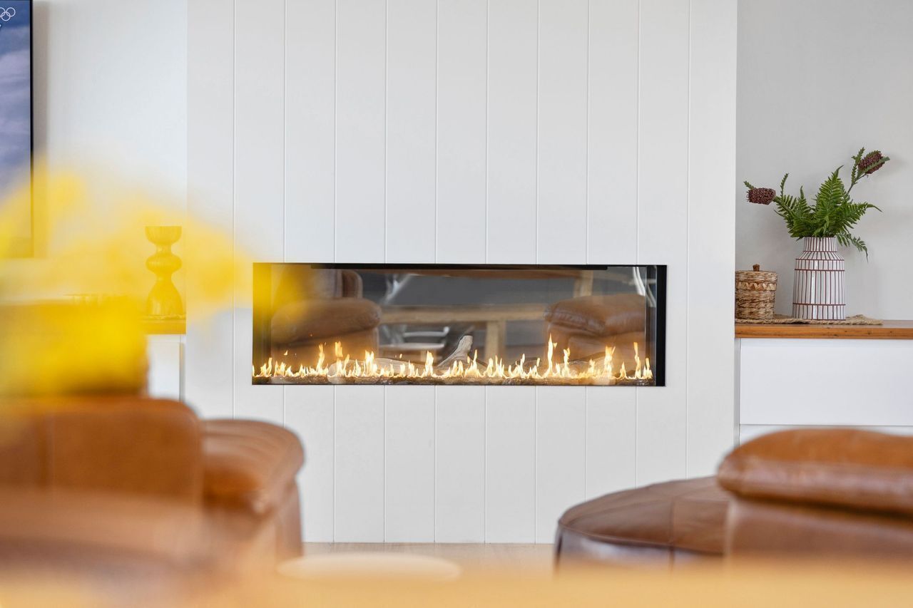Une cheminée moderne, avec un mur blanc aux lignes épurées et une cheminée en bois.