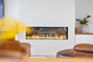 Een moderne haard met een strakke, witte muur en een houten bovenkant.