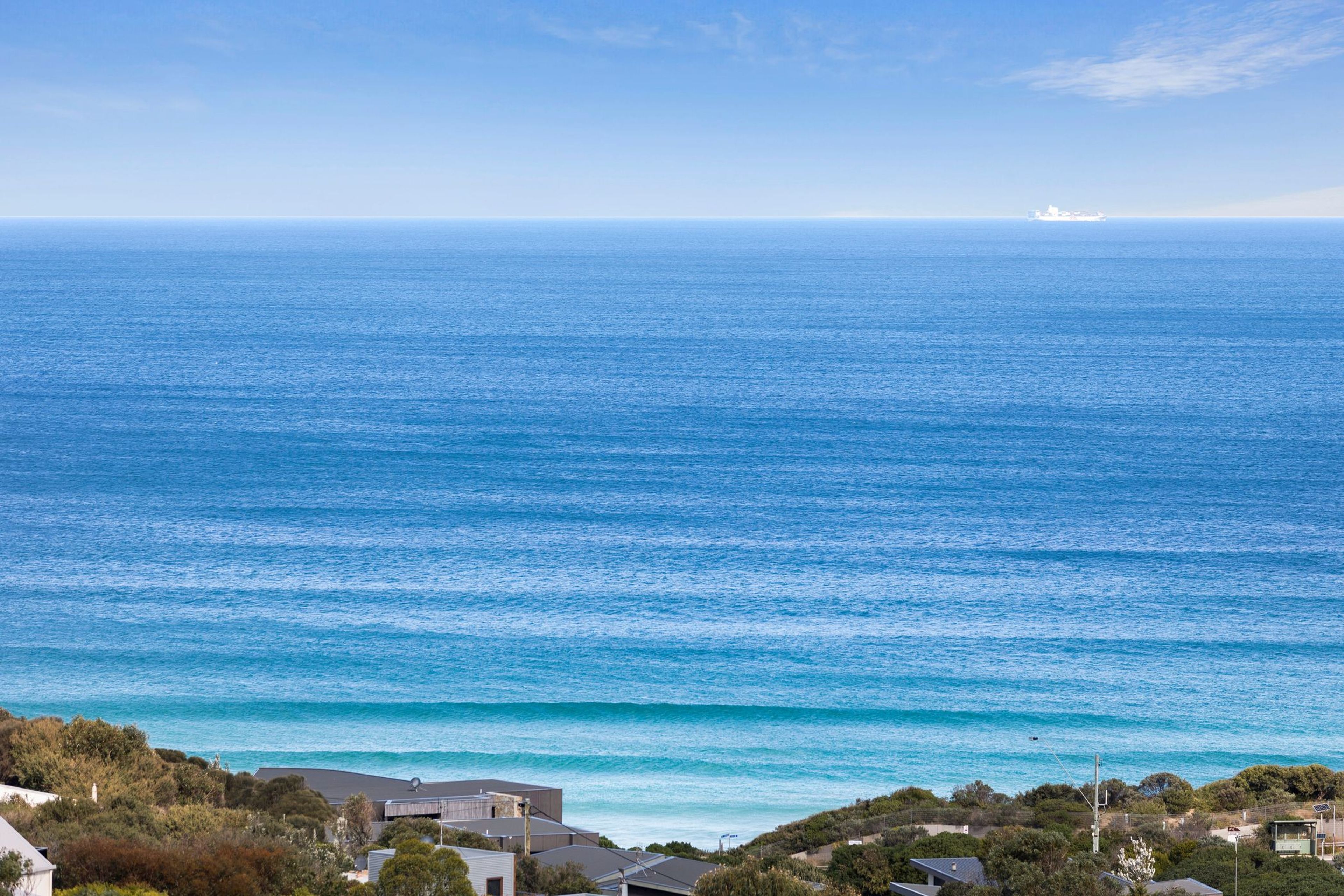 A coastal view with a clear sky, a large body of water, and a distant ship.