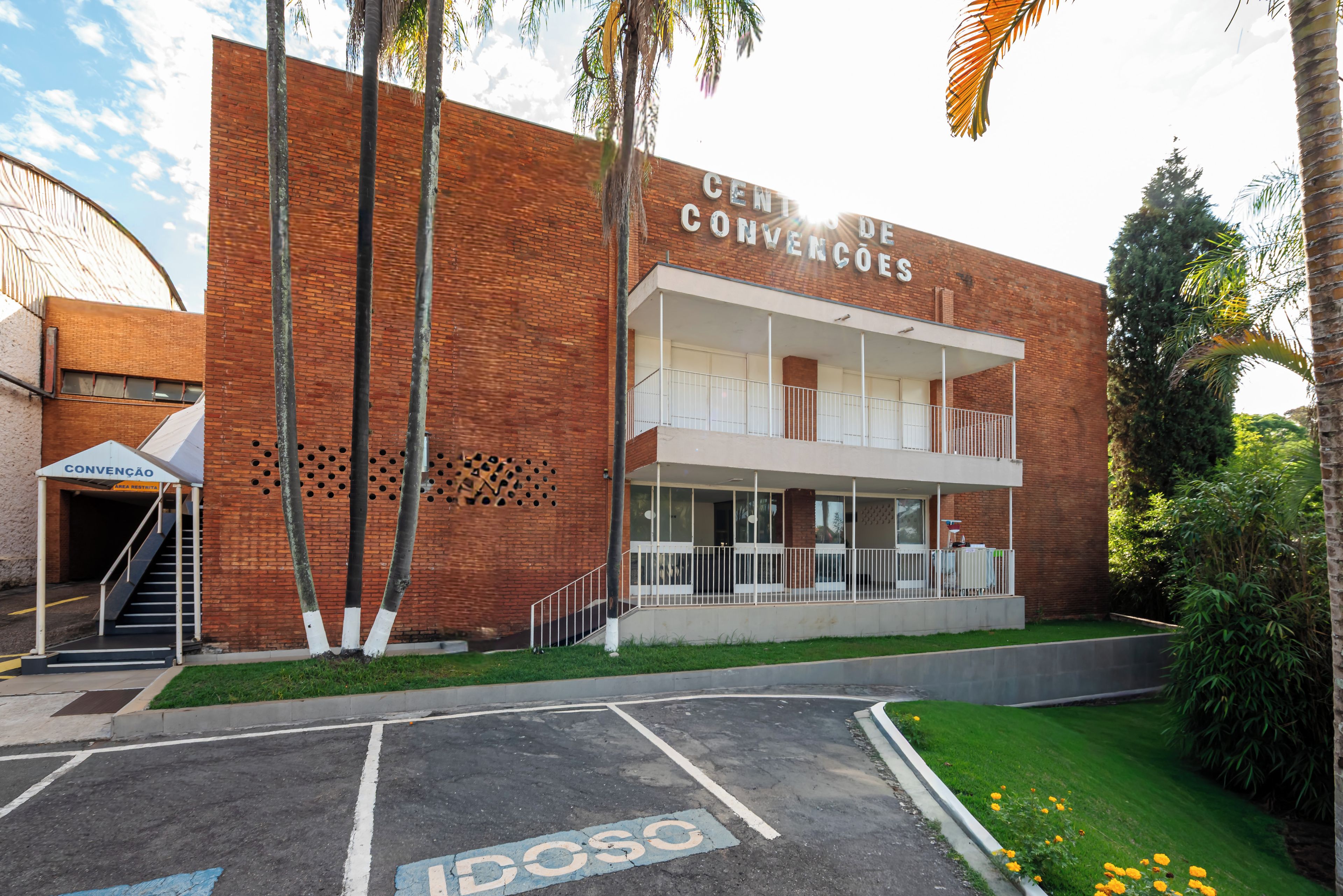 Un edificio con un cartel que dice 'CENTRO DE CONVÊNÇÃO' y un estacionamiento con espacios marcados con la letra 'P'.