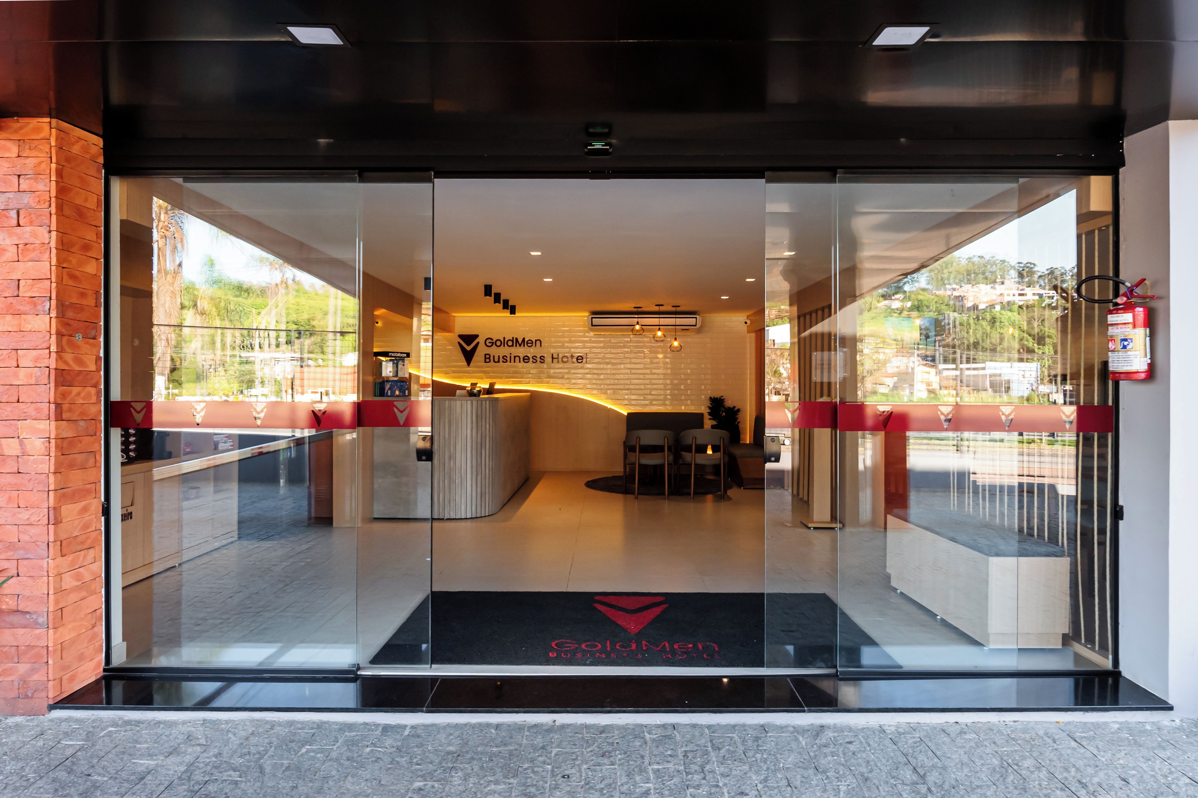 La entrada del Hotel GoldMen Business, con una recepción, zona de estar y vistas al exterior.