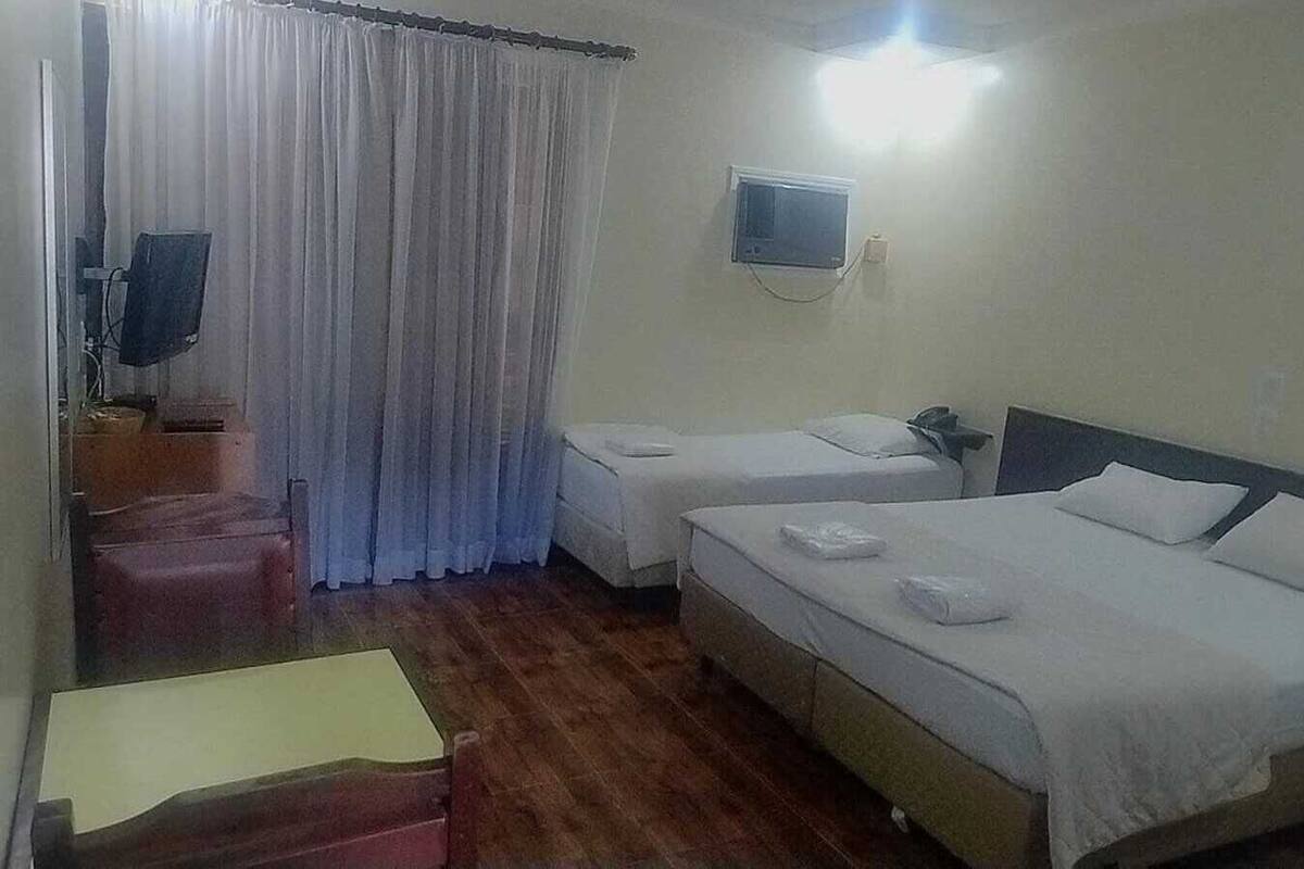 Une chambre d’hôtel avec deux lits, une télévision, un bureau et une chaise.