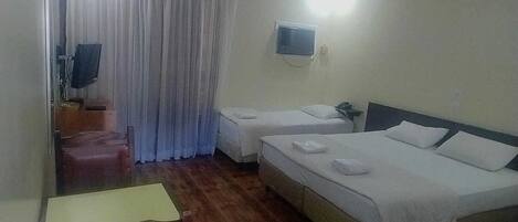 Una habitación de hotel con dos camas, televisión, escritorio y una silla.